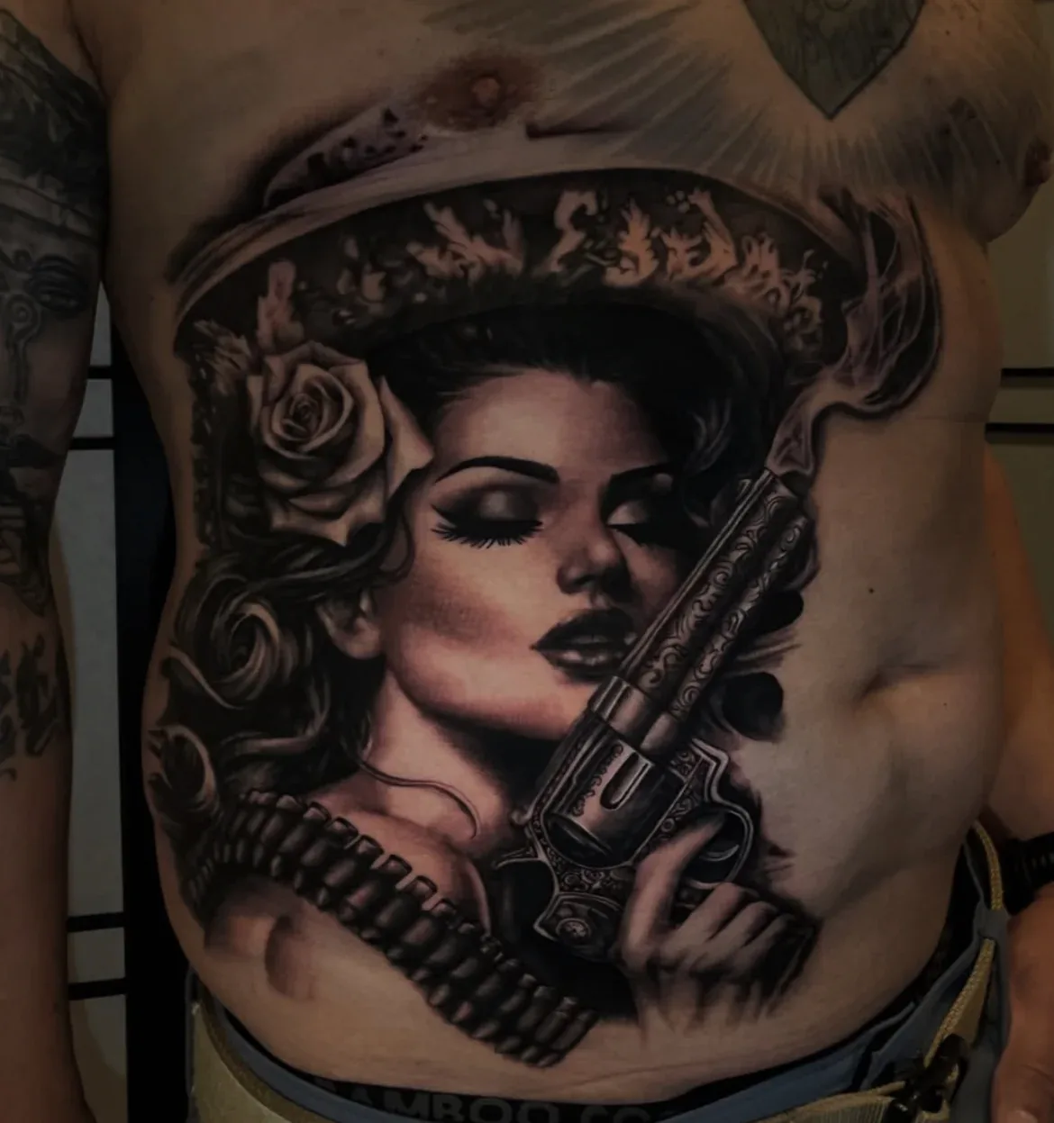 Black-and-grey Chicana portrait tattoo across the torso.